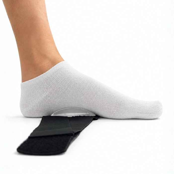A light gray ribbed ankle sock worn on a foot, shown pressing down on a clear curved support pad placed over a black orthopedic heel pad, on a white background.